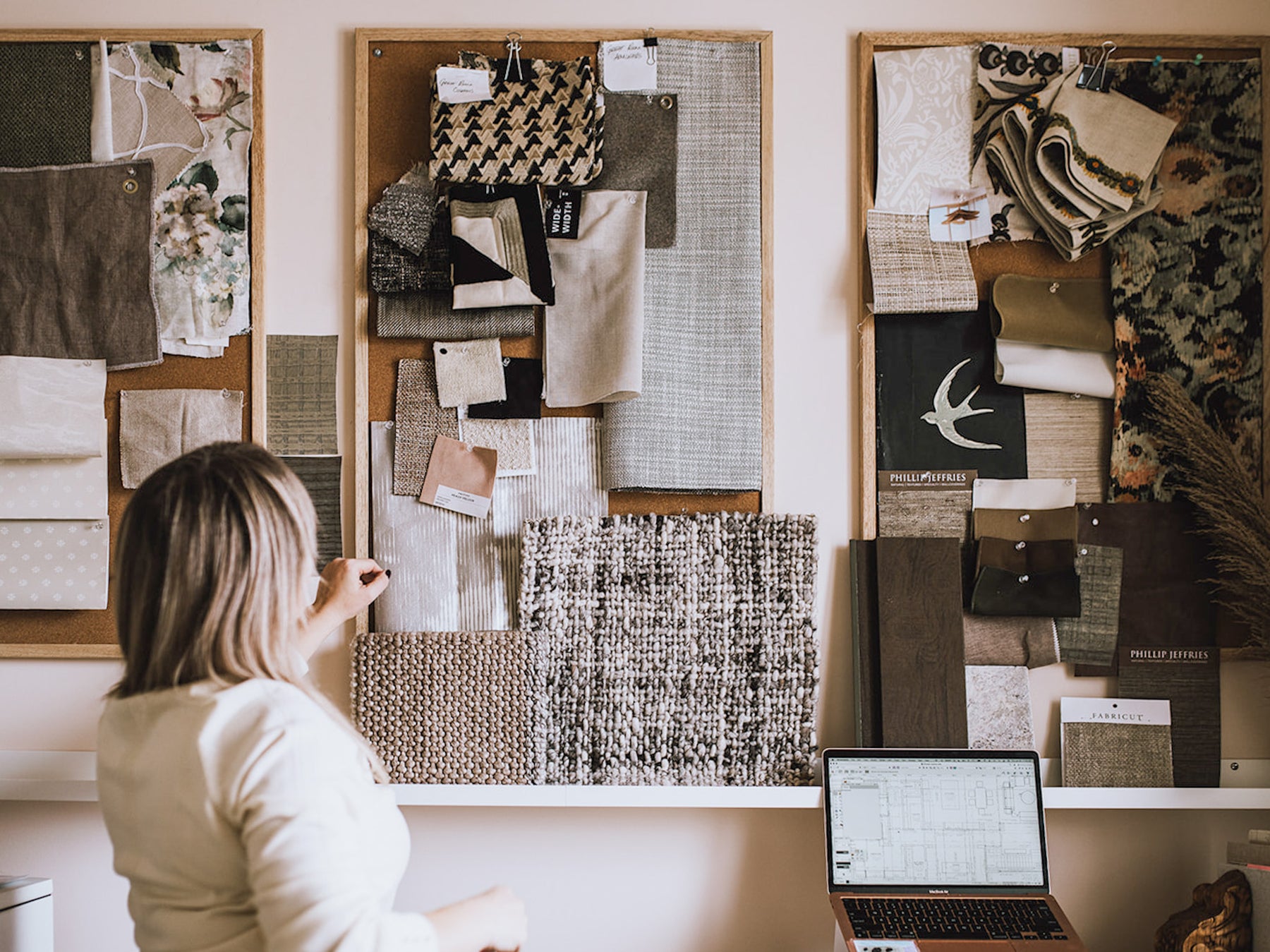 Calgary Interior Designer Heather Draper in her interior design home office adjusting samples on her client moodboards